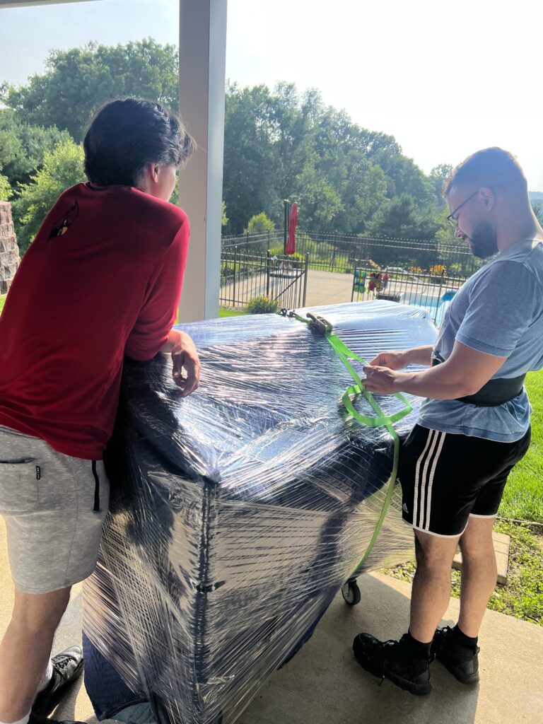 Two Elite Haulerz moving a piano on a sunny day in Michigan 